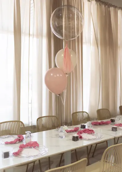 Adult dining table with balloon centerpiece, charger plates and personalized favors