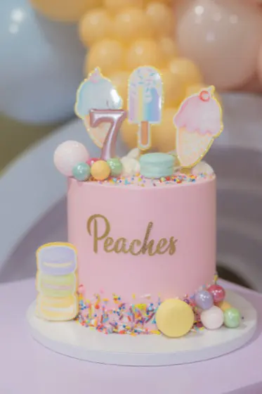 Pink candy-themed birthday cake with ice cream toppers, macarons and sprinkles