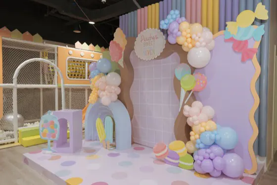 Candy-themed backdrop with a pastel balloon garland, ice cream cutouts and a polka dot platform