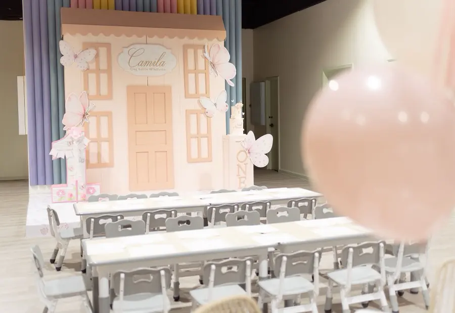 Playville private party room set with kids' tables, chairs and a pastel playhouse backdrop