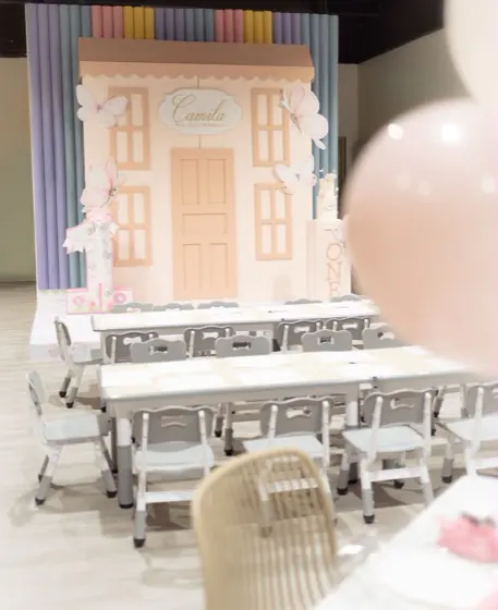 Kids' party tables with custom placemats facing the decorated stage at Playville