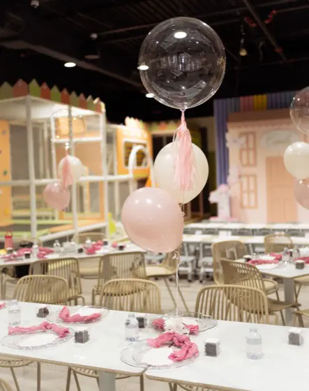 Indoor playground climbing structure next to the decorated party tables at Playville
